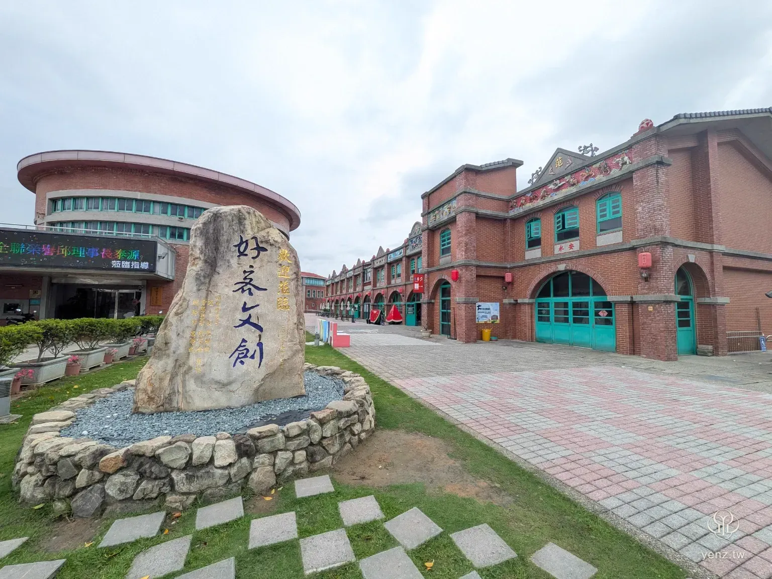 湖口好客文創園區入口，前景為寫有好客文創的石碑，後方是紅磚建築與綠色窗框。