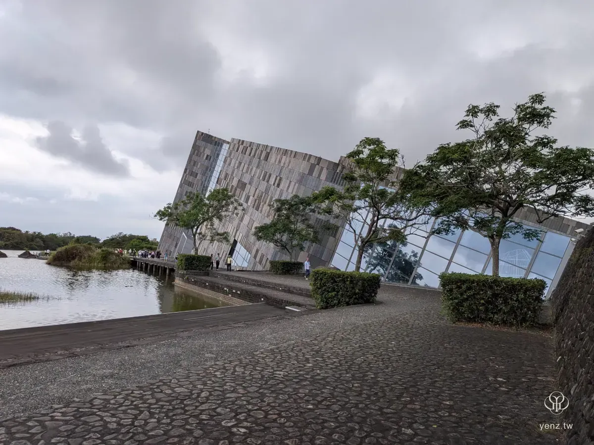走出館外後回看蘭陽博物館，水面、石子路、陰天與建築斜面。