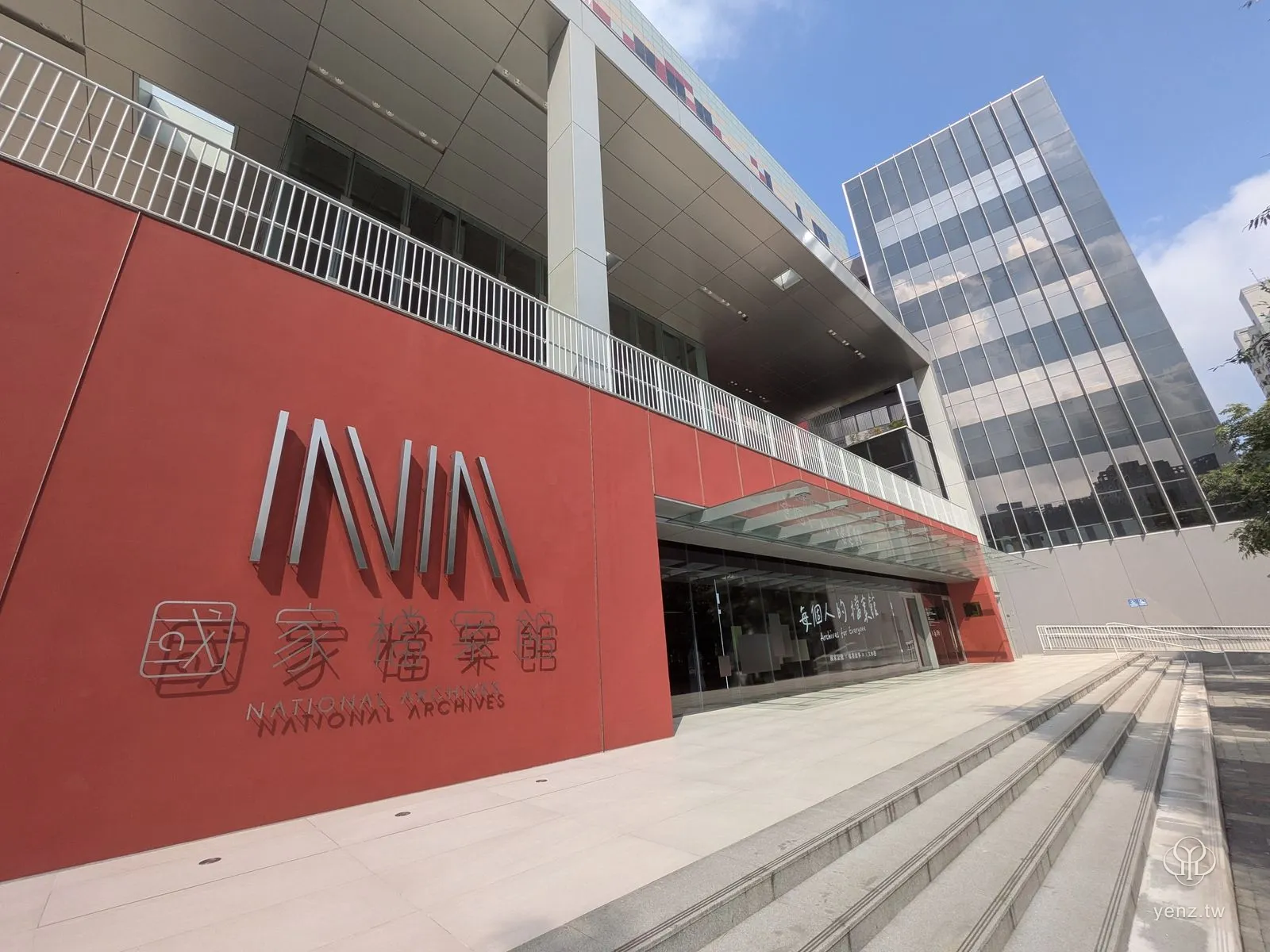 清晨陽光下的國家檔案館正面，紅色外牆與 NATIONAL ARCHIVES 立體字。