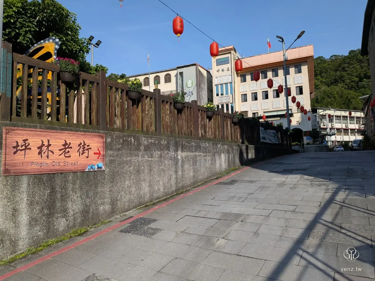 坪林老街入口指標與街道坡面，遠方可見區公所與山景。