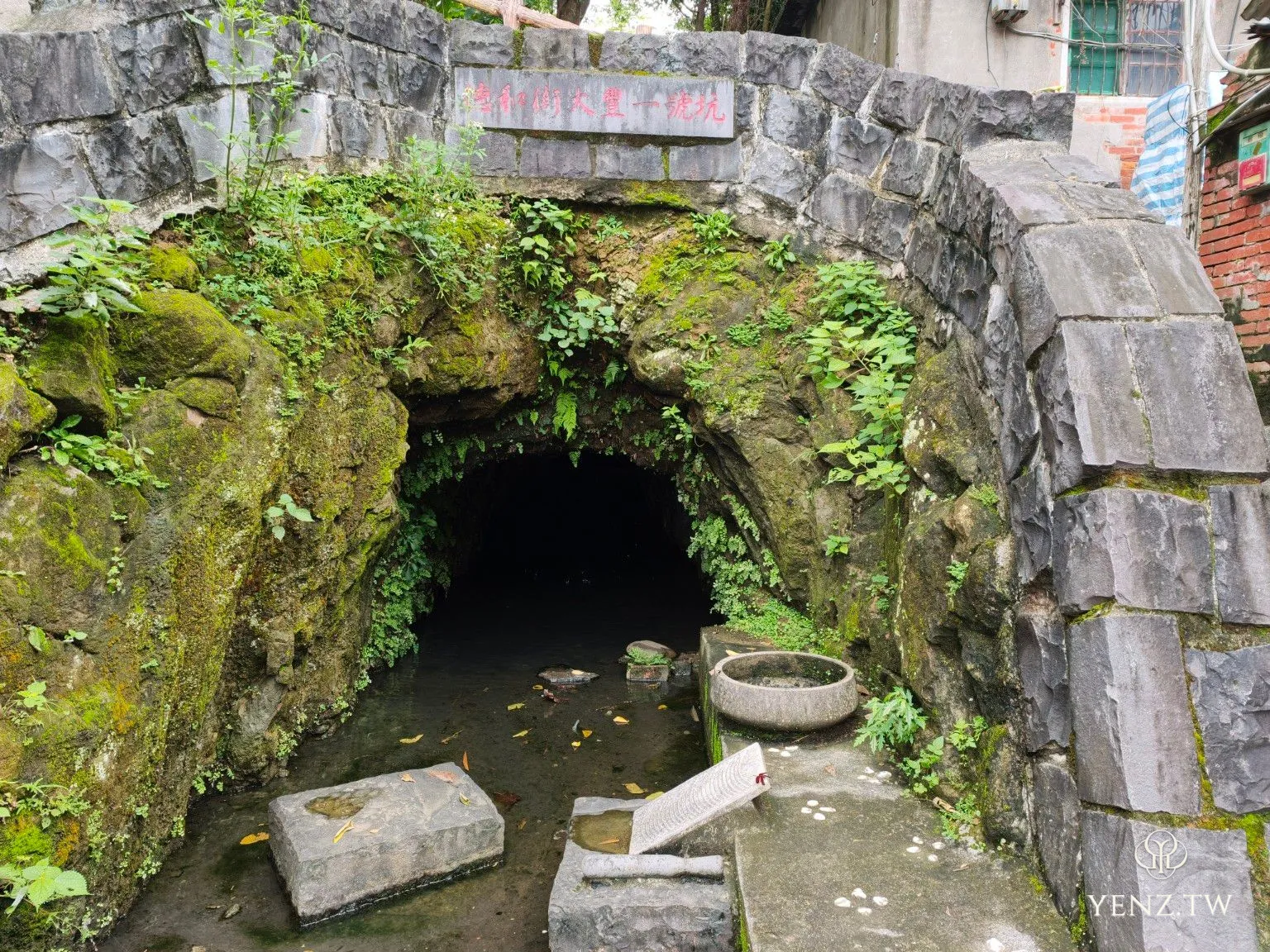 被青苔、蕨類與岩石包圍的大豐一號坑坑口，前方有石製洗衣板。