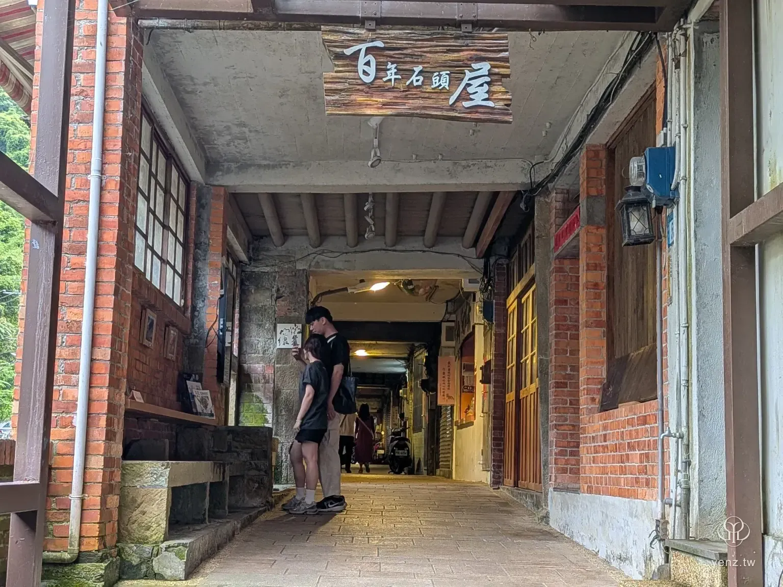 石碇老街旁的百年石頭屋牌示與老街巷道入口。