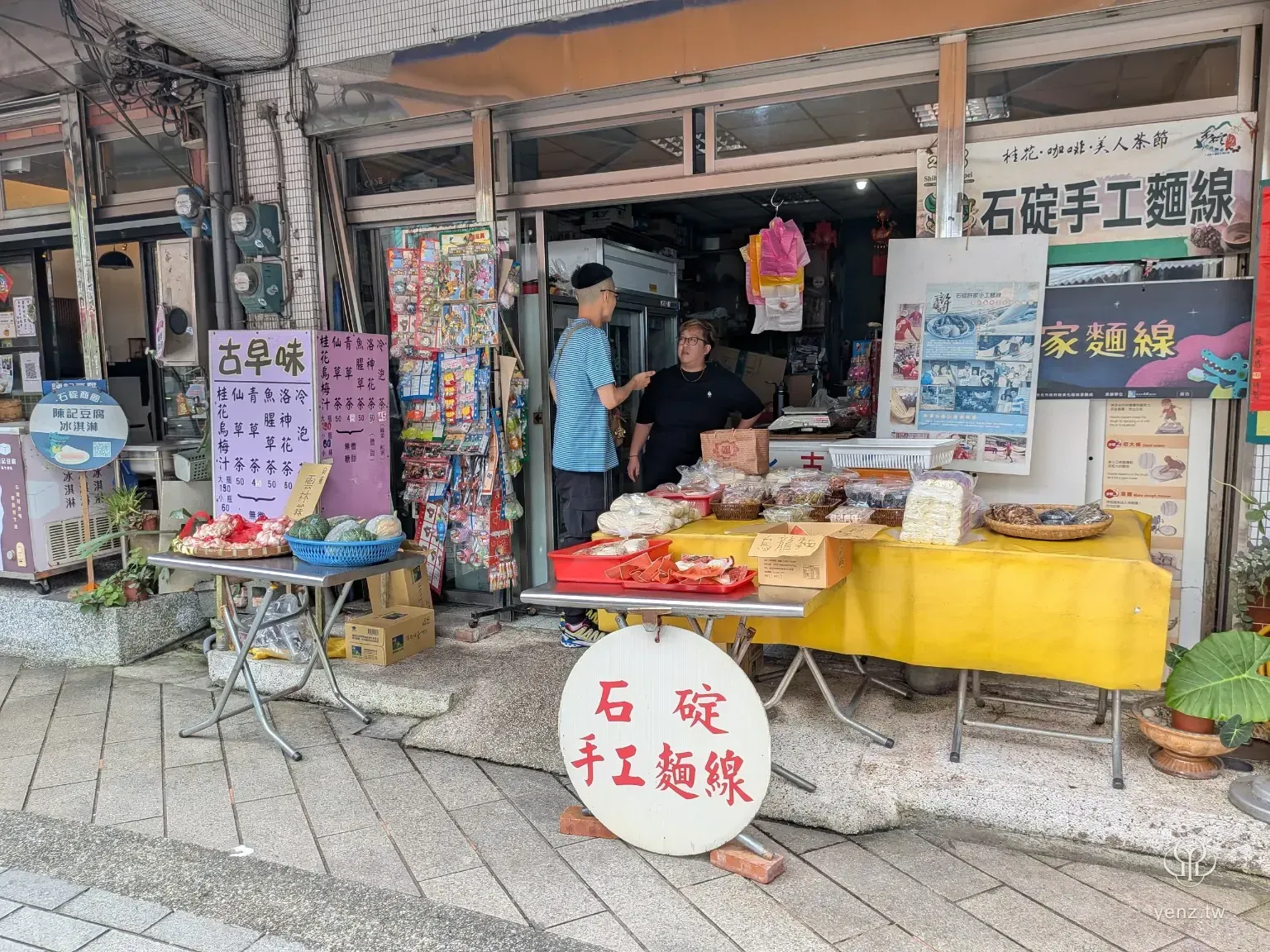 石碇手工麵線老店門口，店家商品、活動資訊與街邊陳列同時出現。