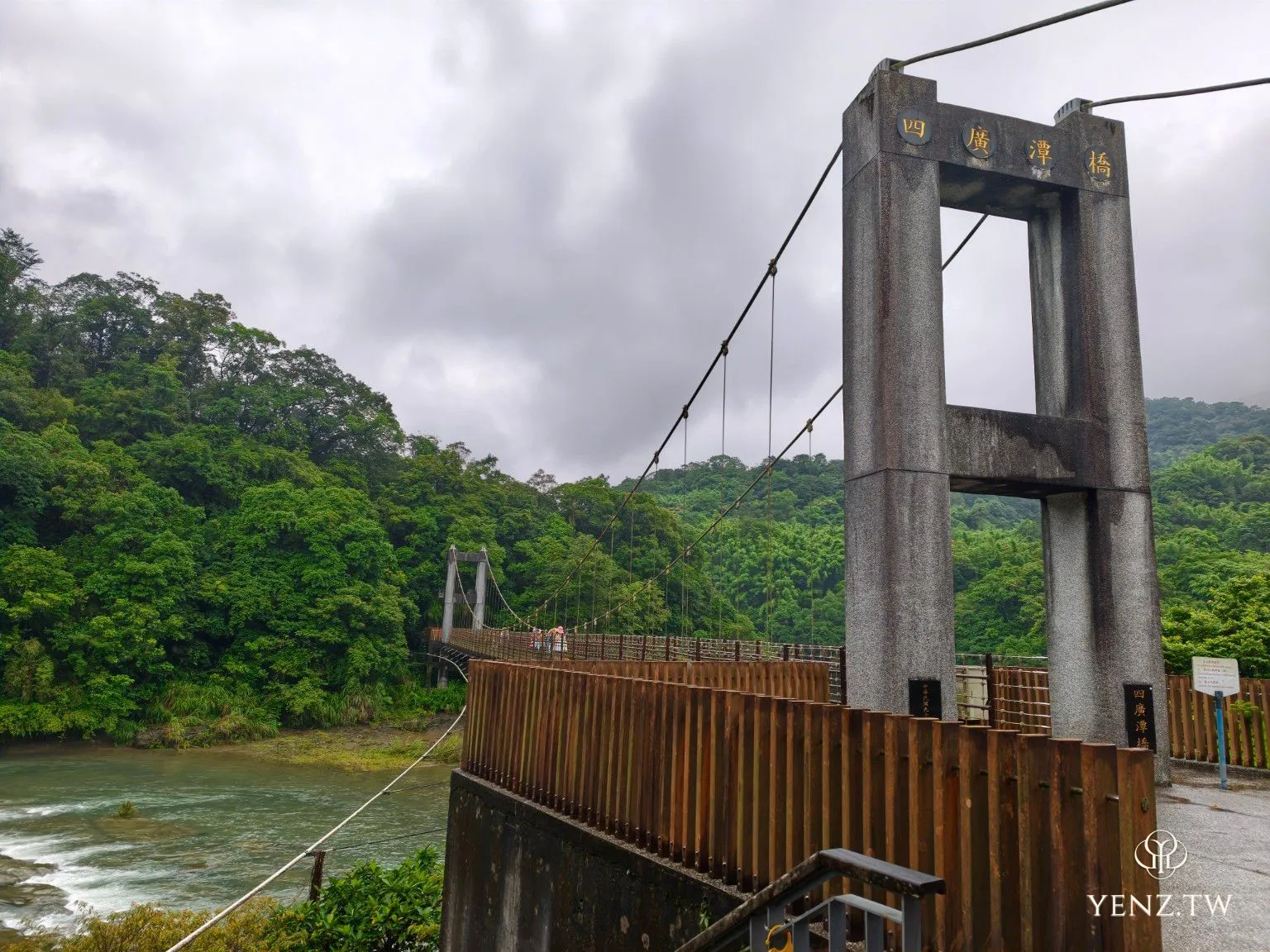 四廣潭吊橋全景，橋塔橫跨基隆河，兩岸是濃綠山林。
