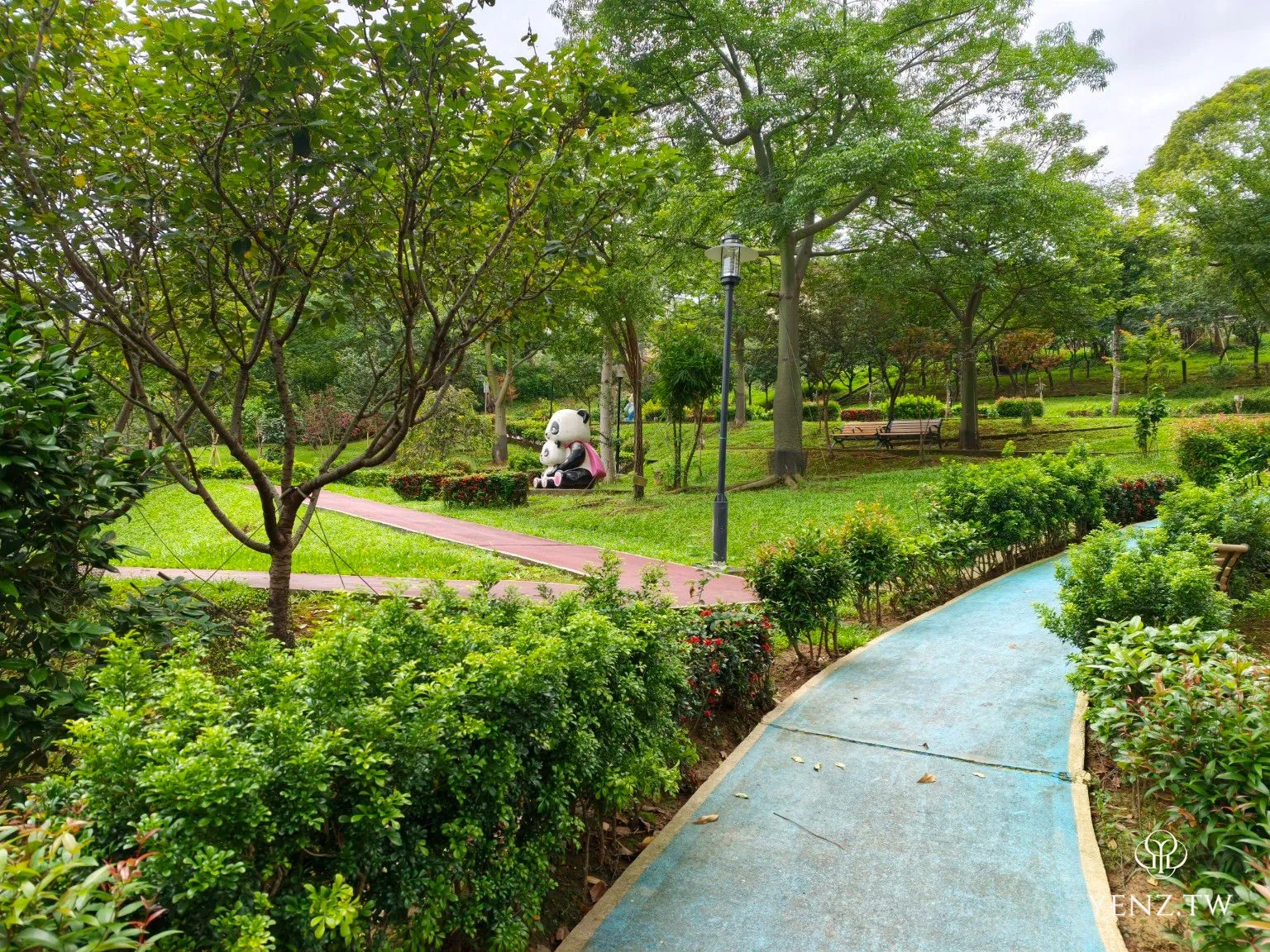 藍色步道、修剪整齊的綠籬與遠處的熊貓造景。