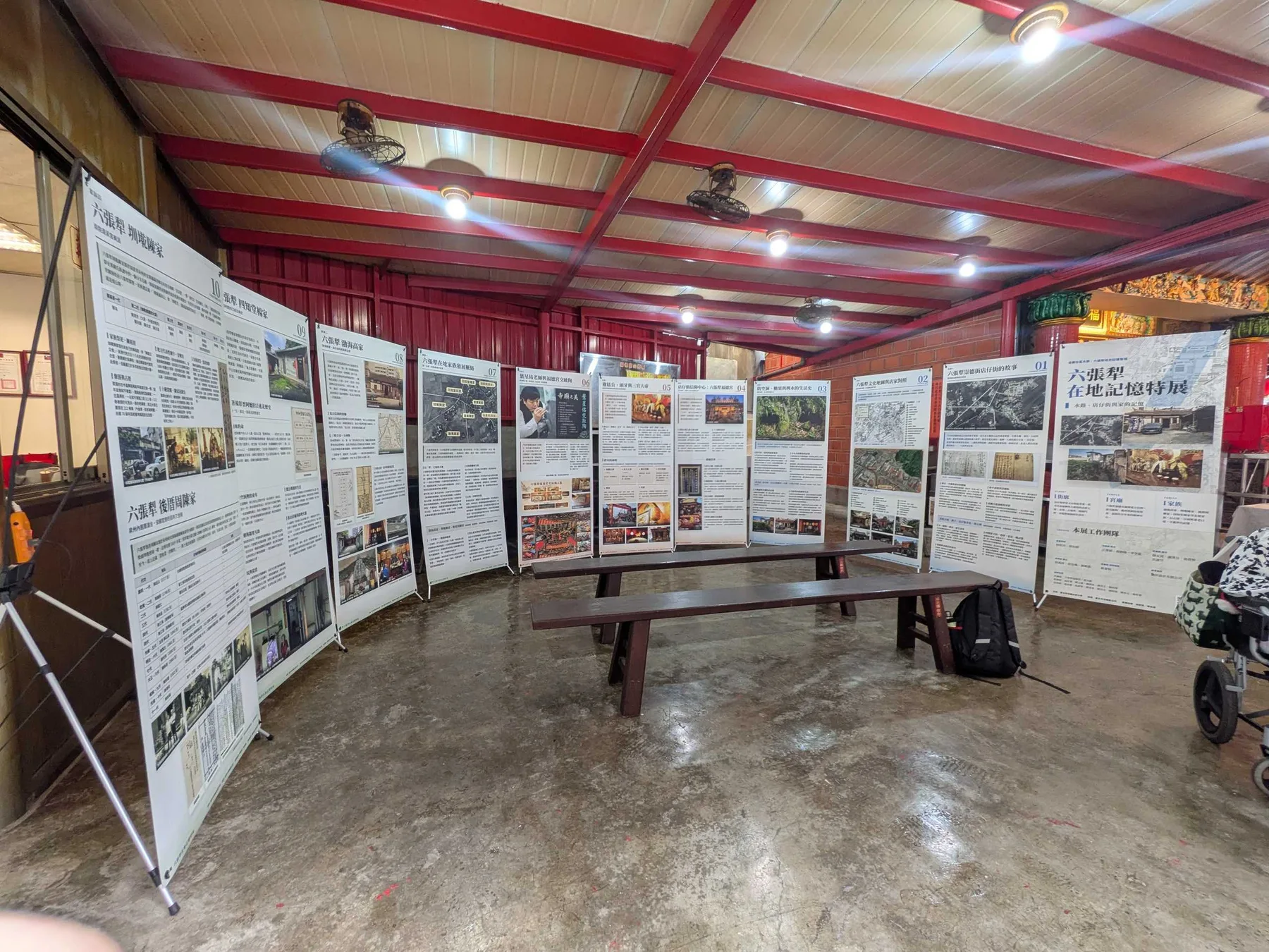 開展前的廟埕展場，九件展板與主視覺沿弧線排開，無人時的全景。