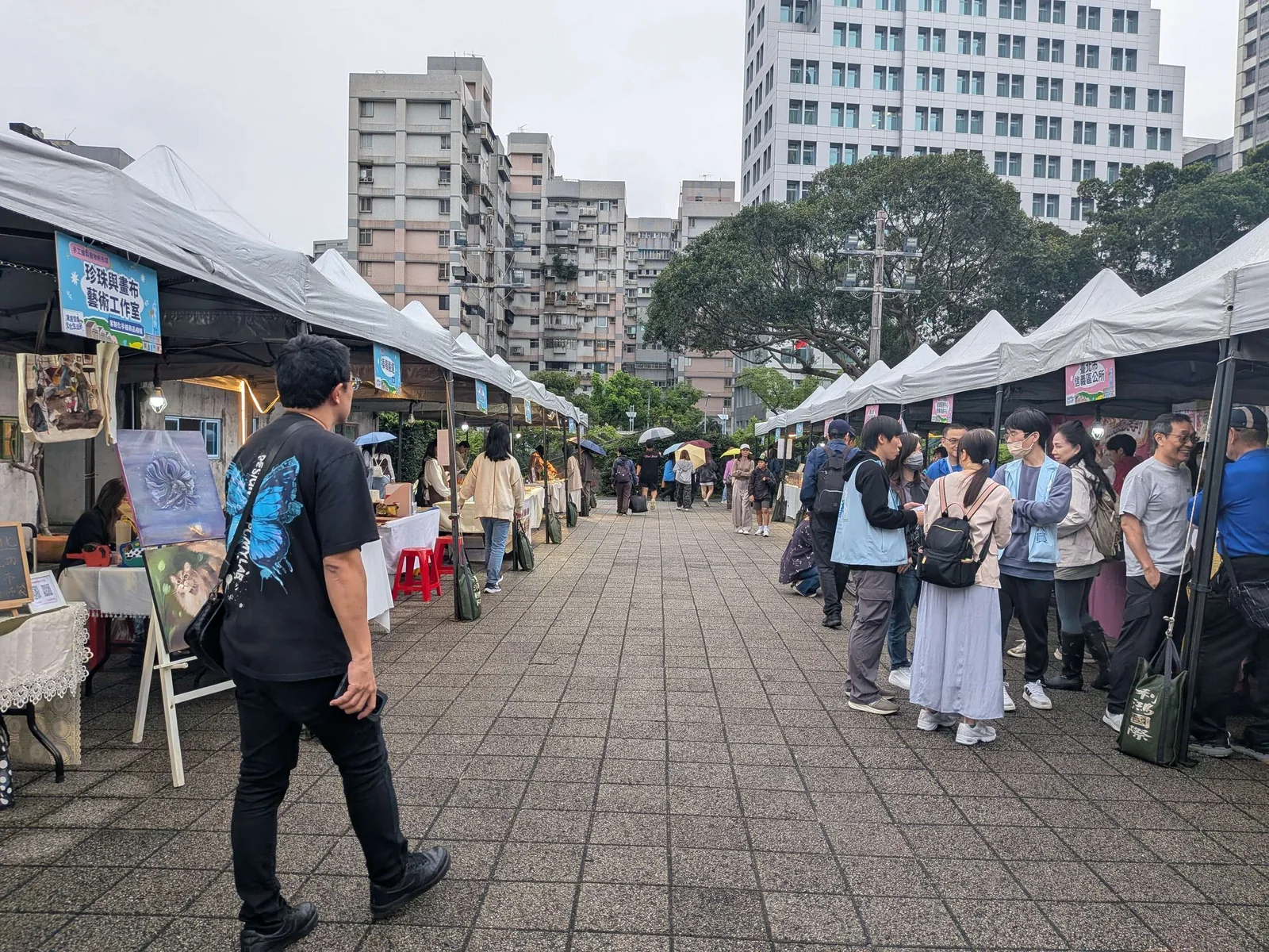 漫遊信義文化生活節市集現場，手工藝攤位沿廣場兩側展開，人潮在攤位間穿梭。